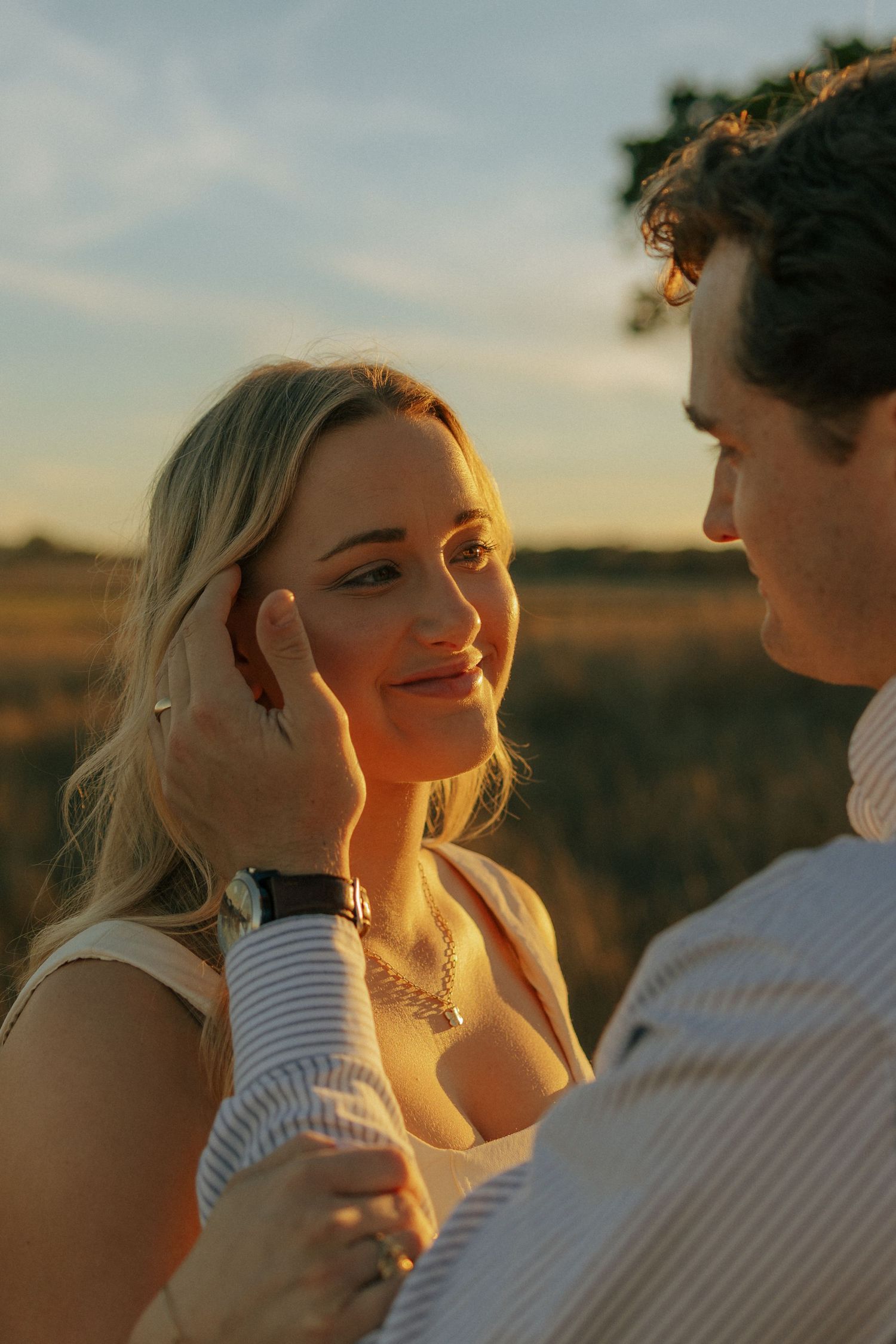 Golden sunset light illuminates couple sharing an intimate moment in nature.