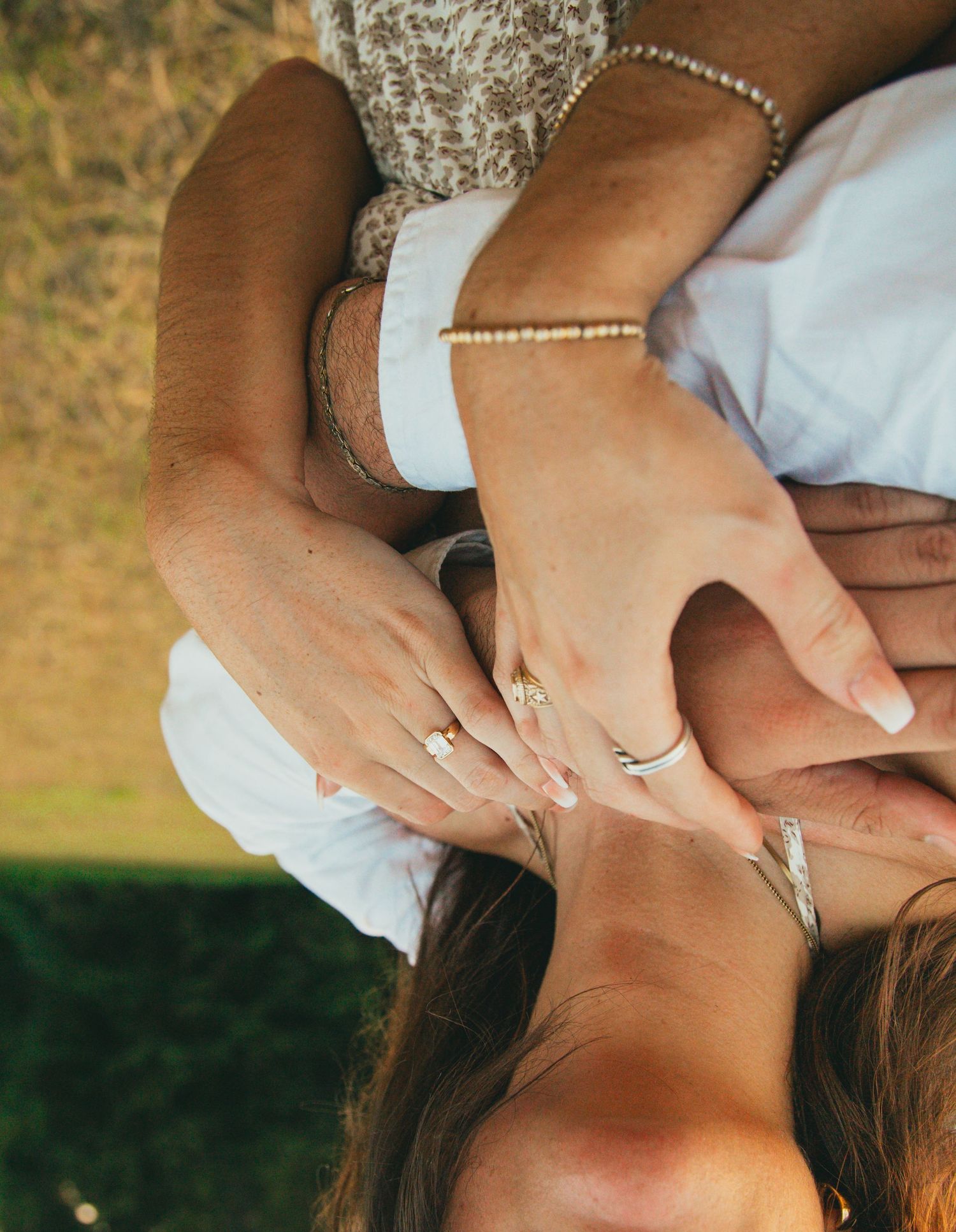 Close-up shot of hands with engagement ring in warm sunlight.