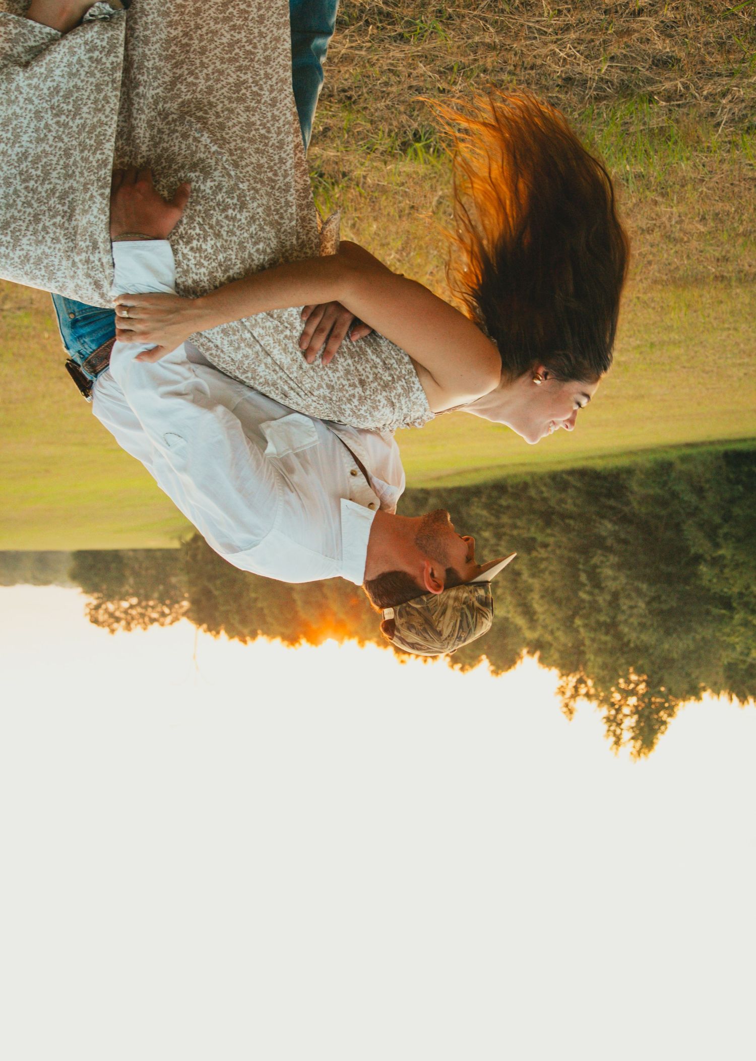 Couple embracing in golden sunset light during outdoor celebration.