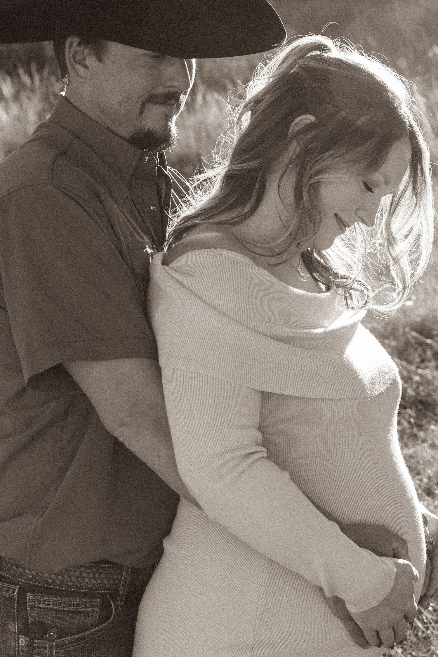 A couple shares an intimate moment in black and white photography outdoors.