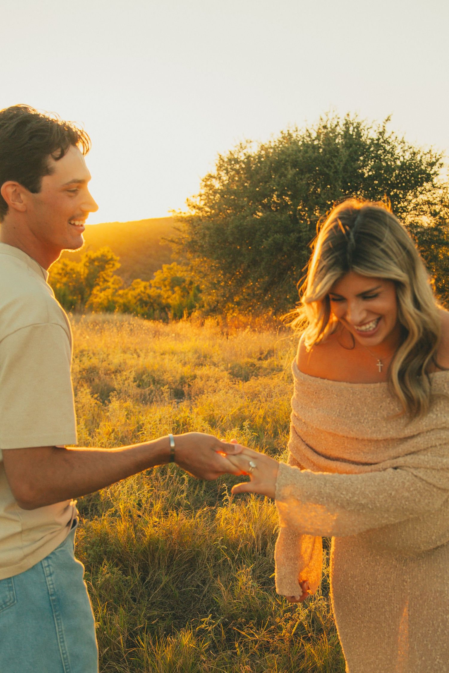Candid moment between couple during sunset maternity photoshoot in a field.