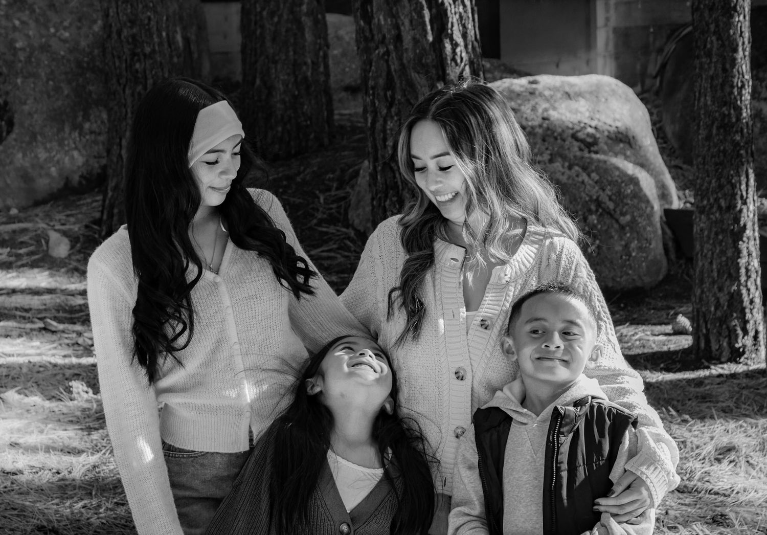 Black and white portrait of two women and two children smiling together outdoors.