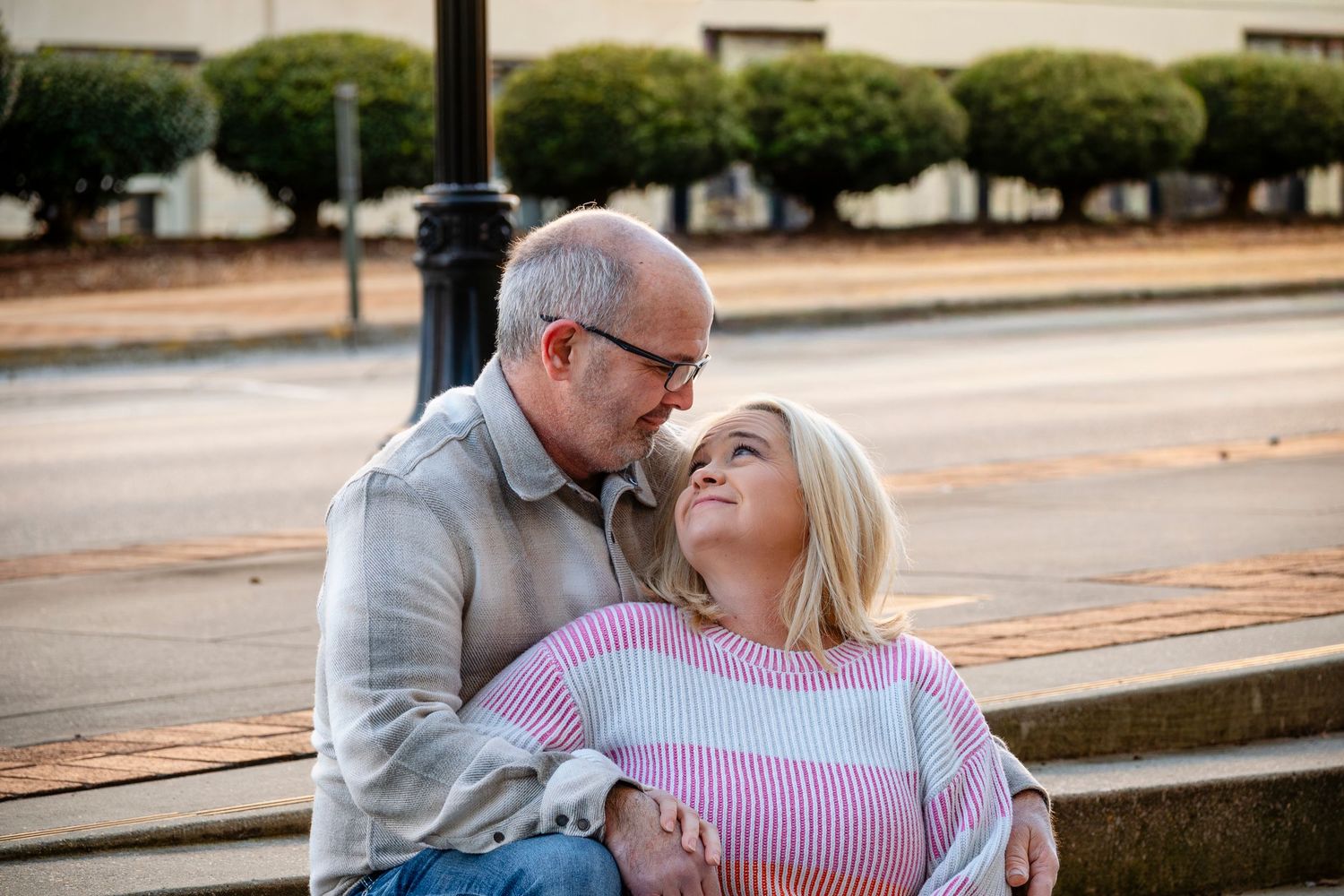 Romantic older couple sharing a tender moment seated outdoors on a sunny day.