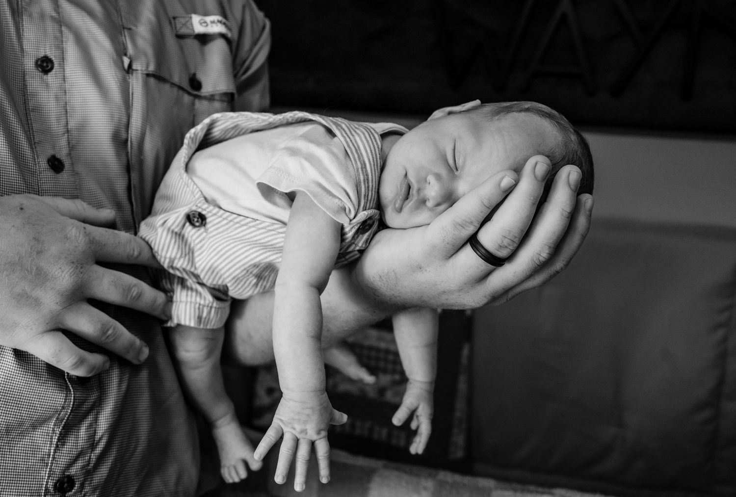 Black and white photo of a newborn baby being cradled in an adults hands.