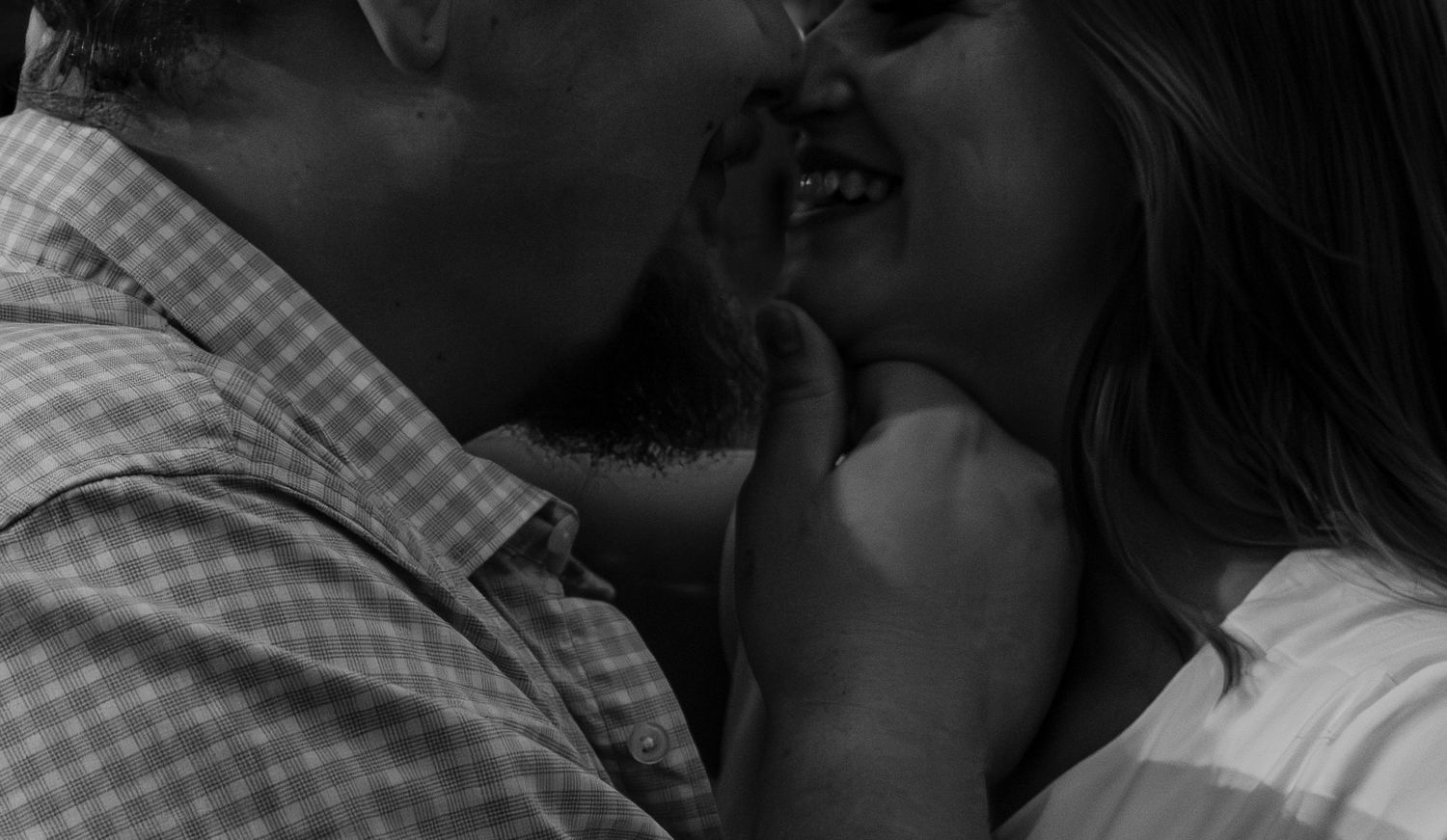 Close-up black and white photo of a couple sharing a romantic kiss.