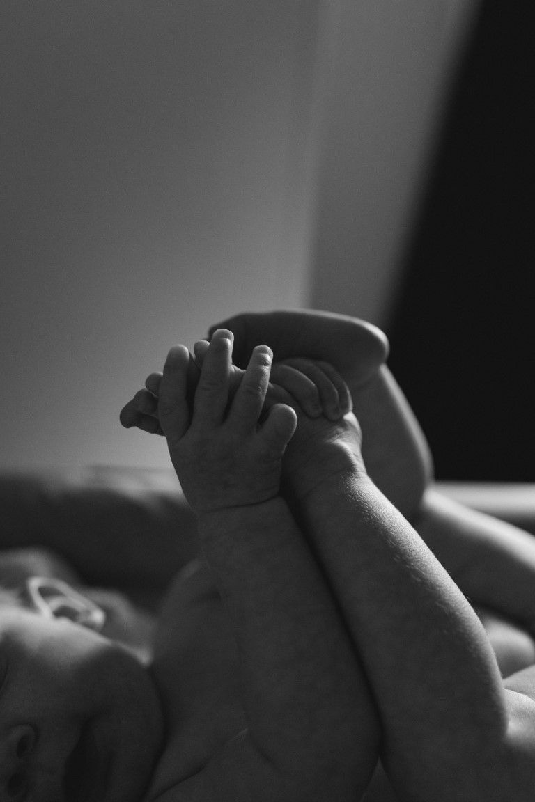 Photo en noir et blanc des pieds et mains d'un nourrisson lors du changement de sa couche à côté de Saint Lô.