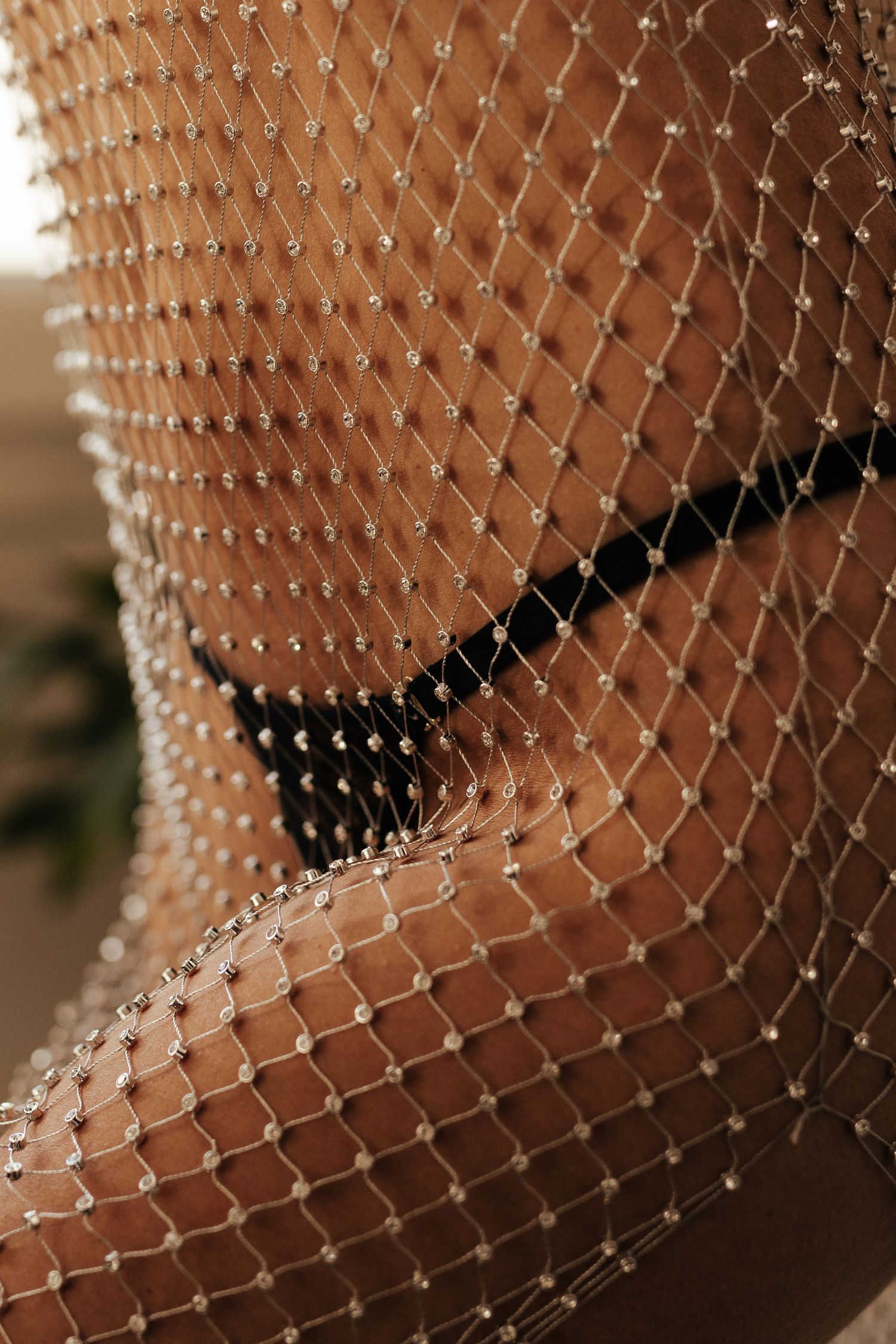 Close-up of a sparkling rhinestone fishnet overlay draped over skin, creating an elegant and glamorous textured effect.