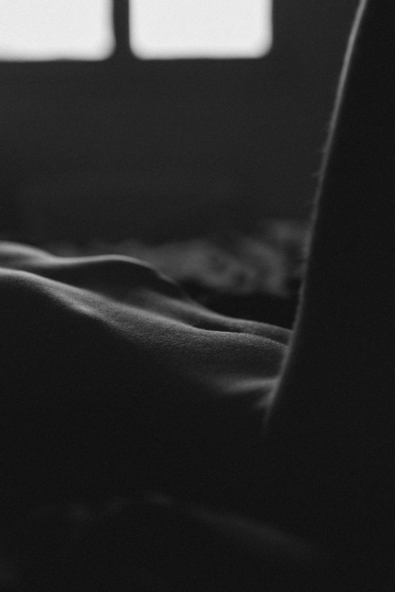 Photographie artistique en noir et blanc, gros plan, des courbes douces du corps humain, jouant sur les ombres et la lumière.