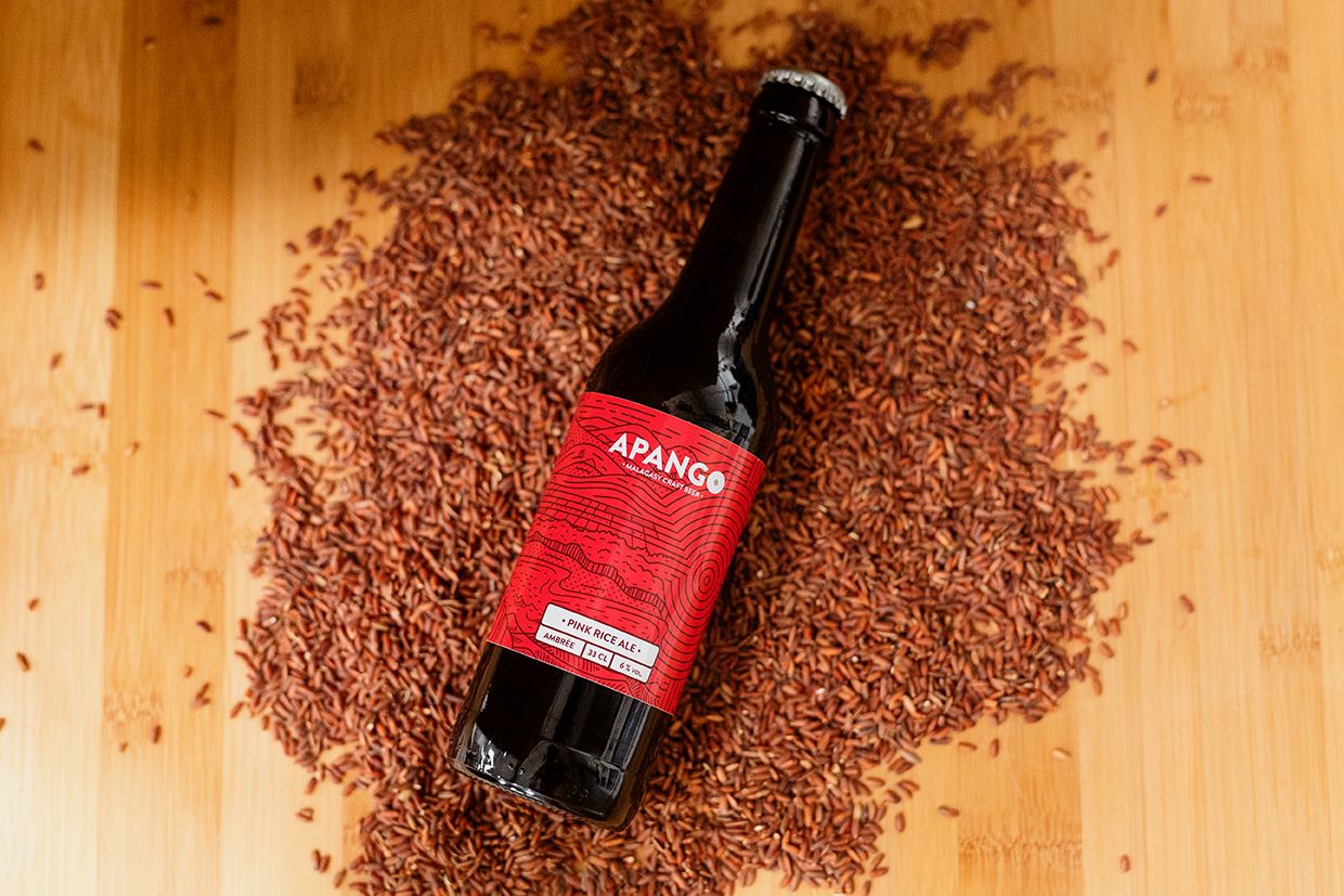 Apango craft beer bottle surrounded by red flax seeds on a wooden surface.