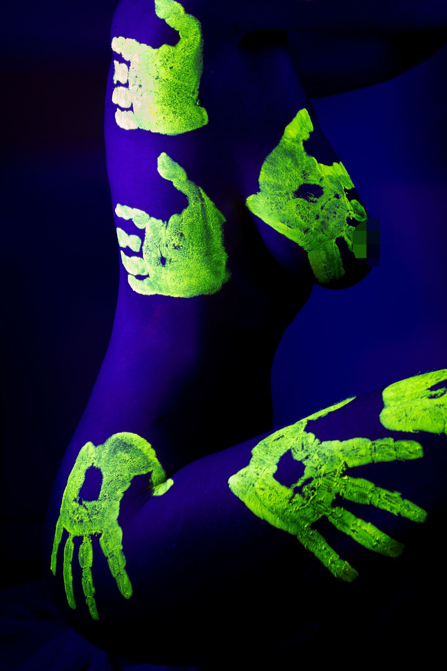 Photographie artistique sous lumière UV montrant des empreintes de mains fluorescentes vertes sur des jambes féminines sous lumière noire.