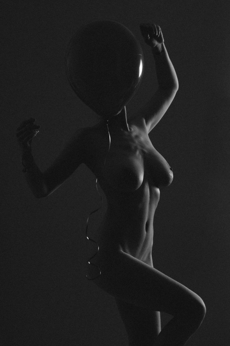 Silhouette saisissante en noir et blanc d'une femme nue tenant un ballon à col, photographie artistique de studio.