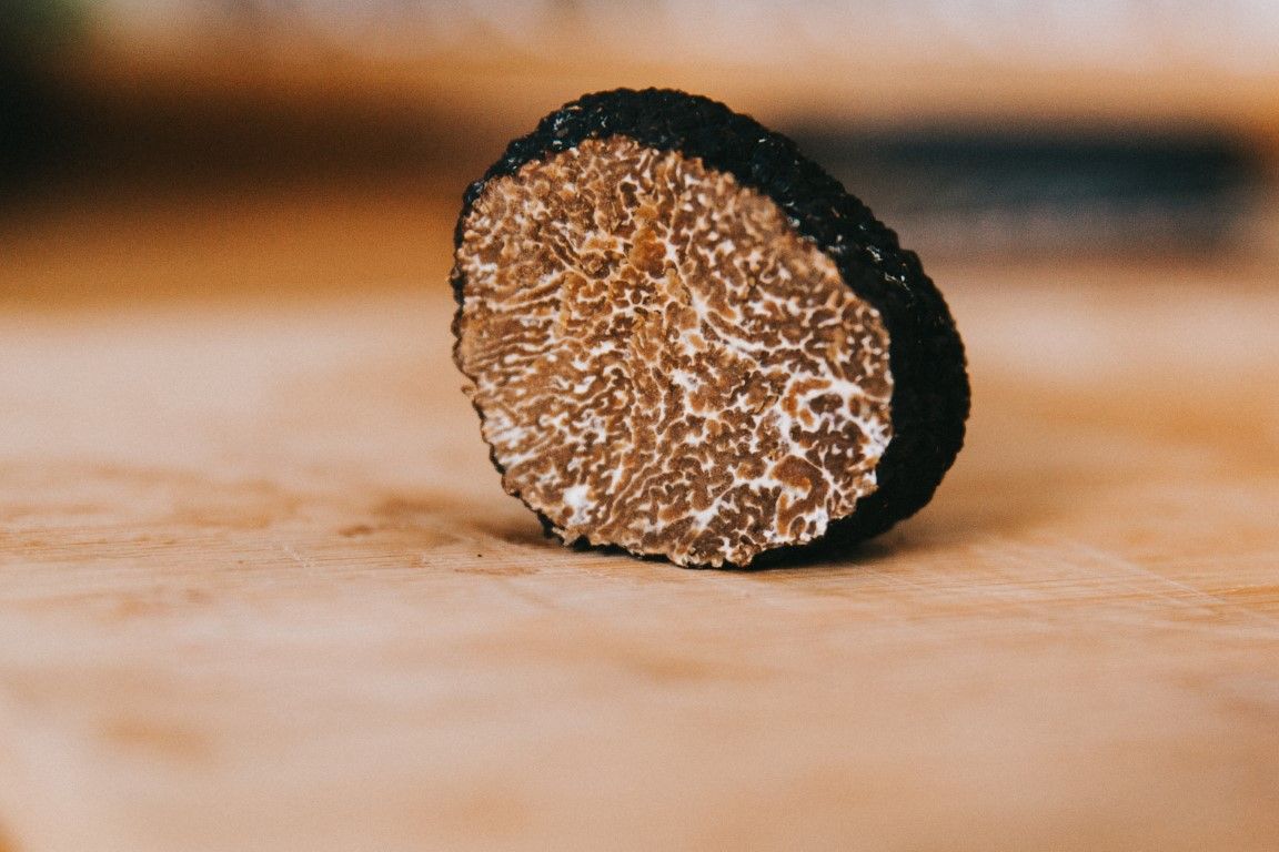 Cross-section of a black truffle on a wooden surface revealing its intricate brown marbled interior.