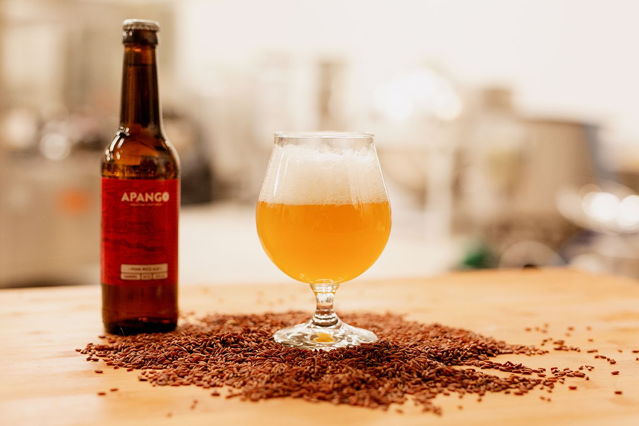 Apango craft beer bottle and tulip glass with golden ale surrounded by flax seeds.