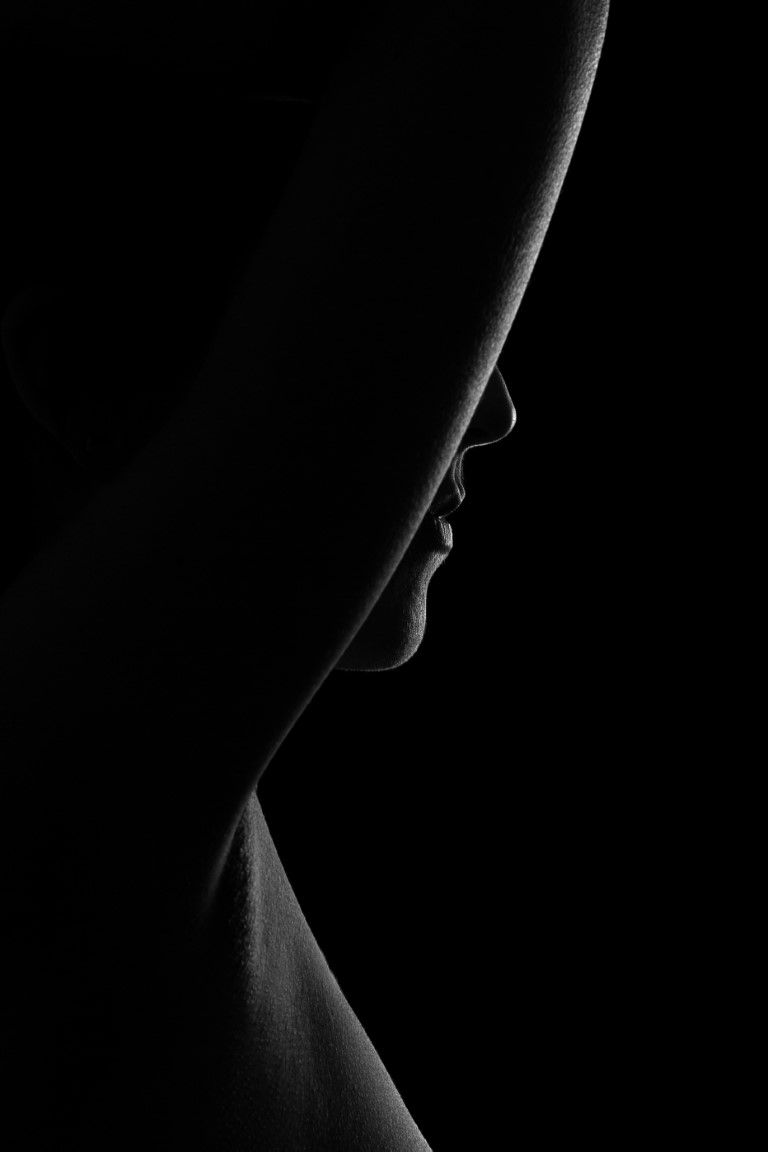 Black and white profile silhouette of a womans face in dramatic low key lighting.