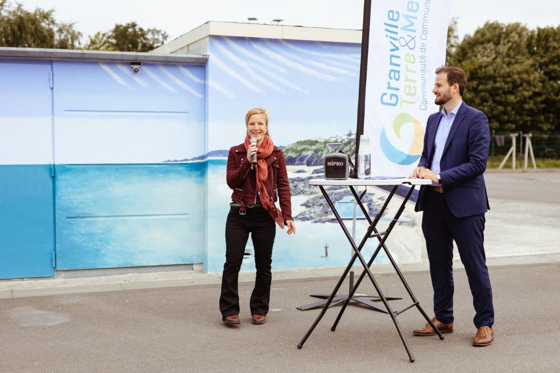 Two professionals speaking at an outdoor event near a Granville branded banner and display stand.