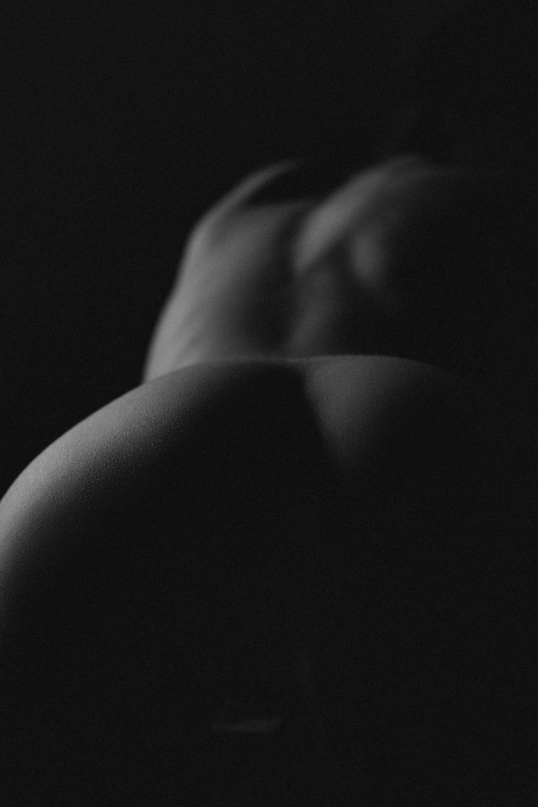 Photo de nu artistique en noir et blanc d'une femme vue de dos avec une lumière très douce.