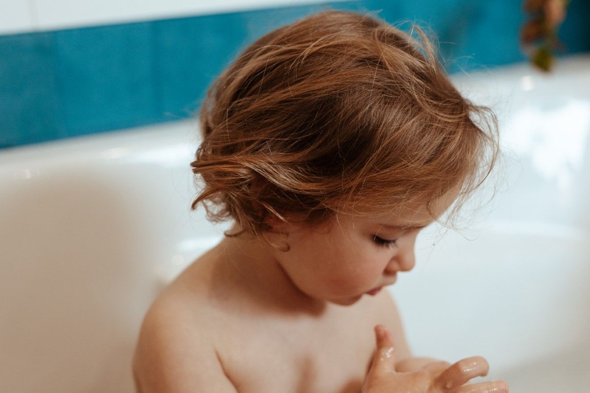 Petite fille avec des jolies boucles dans son bain.