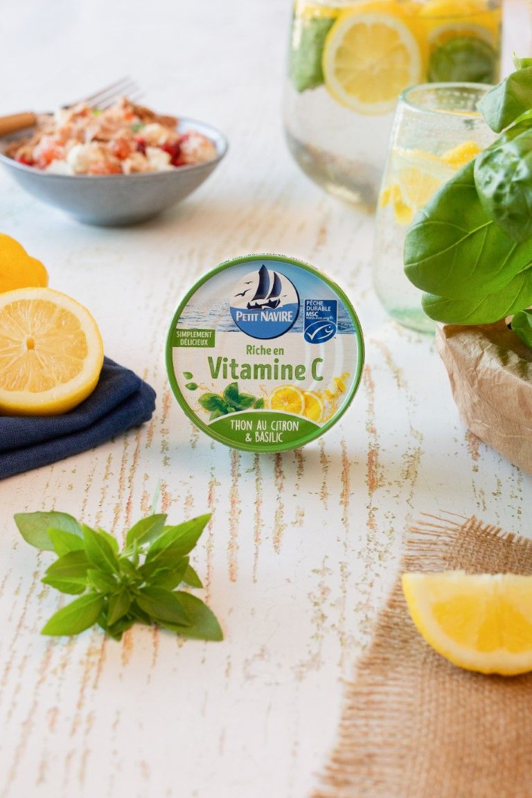 Petit Navire Vitamine C tuna can with lemon and basil beside fresh citrus and water.