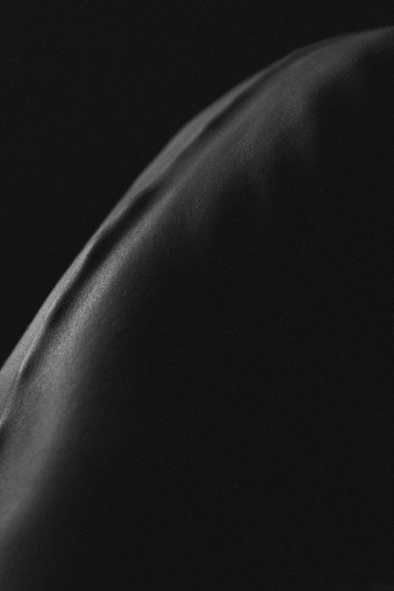 Gros plan d'une photo abstraite en noir et blanc mettant en valeur une surface lisse et incurvée du dos d'une femme