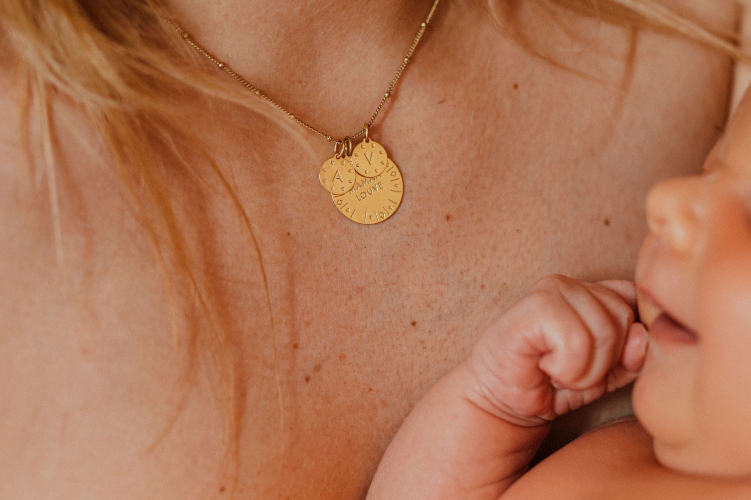 Gros plan sur une femme portant un collier de pièces d'or et tenant un nouveau-né.