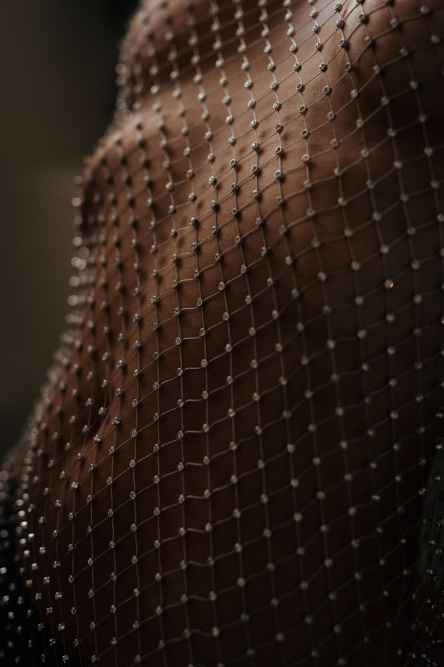 Close-up of a sheer black mesh fabric adorned with tiny silver beads, draped elegantly over a curved surface.