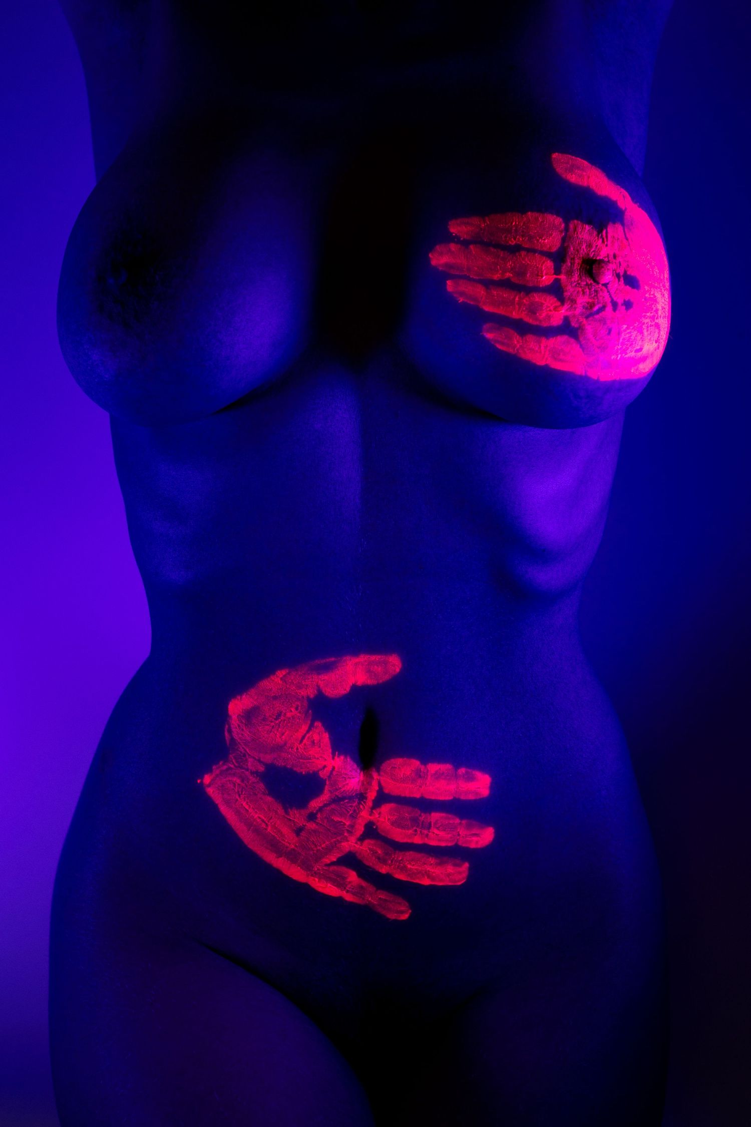 Artistic UV blacklight photography featuring fluorescent neon hand prints glowing on a female torso in purple light.