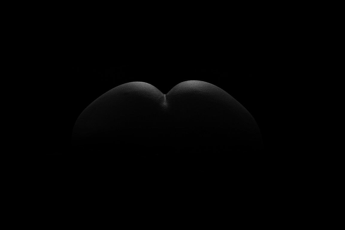 Two dark spherical shapes subtly lit against a black background in a minimalist fine art photography composition.