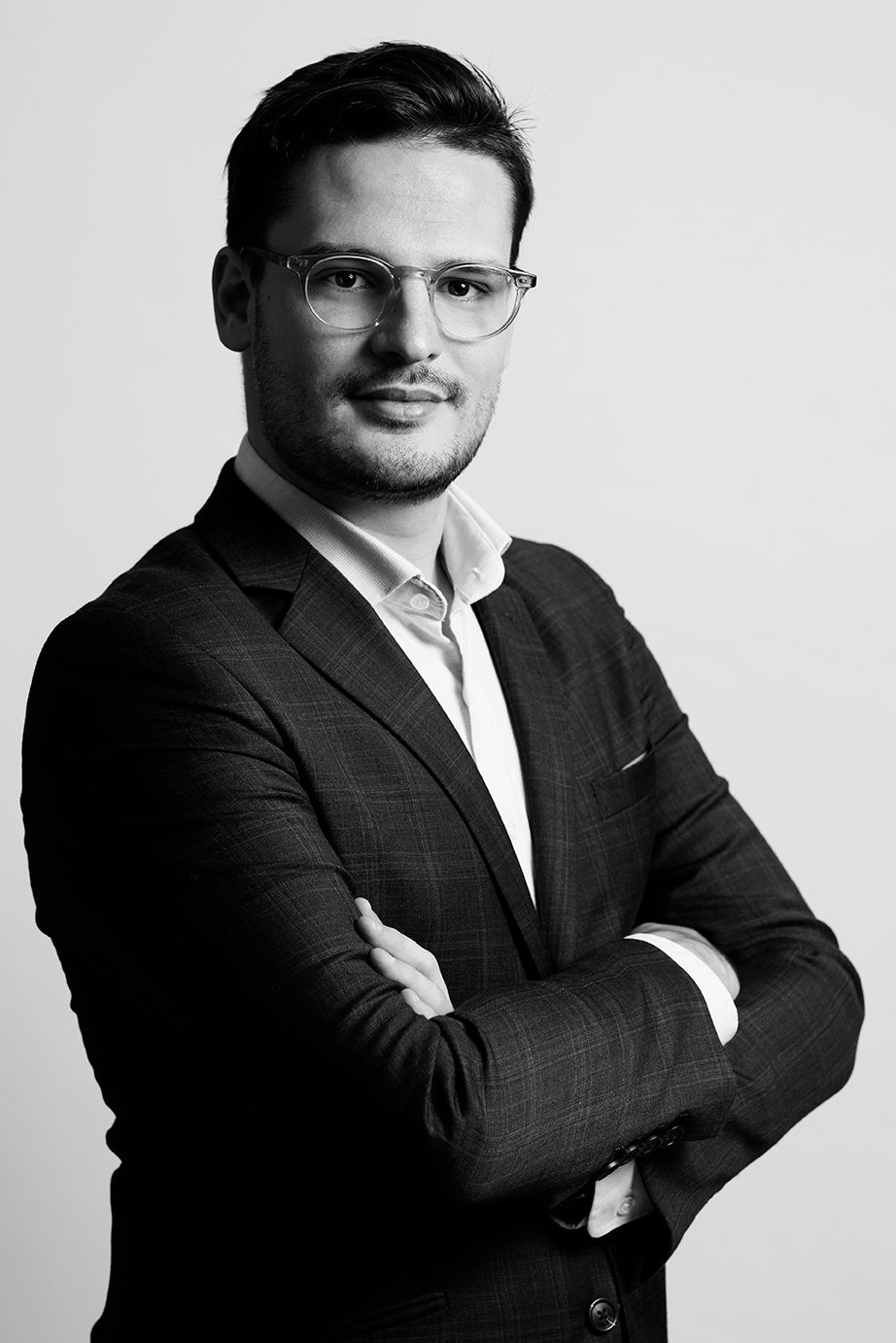 Young professional man in suit with arms crossed in black and white portrait photo.