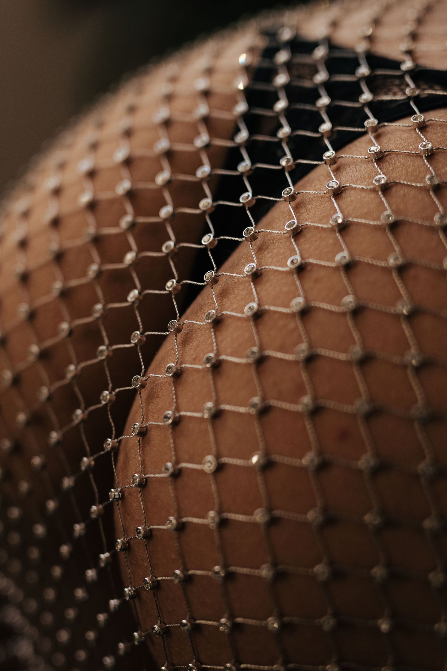 Close-up of sparkling rhinestone fishnet stockings on skin, showing diamond-shaped mesh pattern with crystal embellishments.