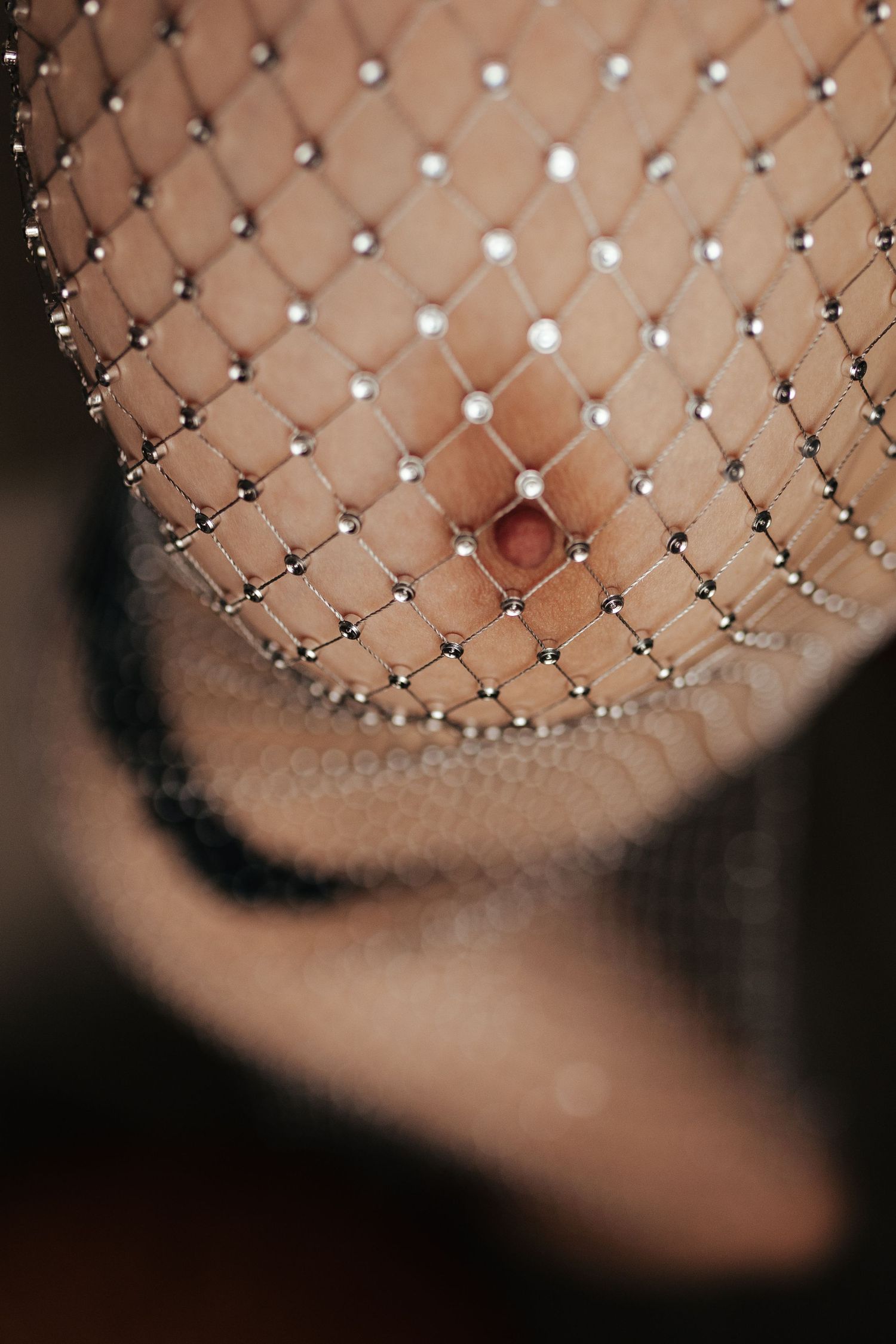 Close-up of a decorative bridal birdcage veil adorned with pearl and crystal embellishments on fine mesh netting.