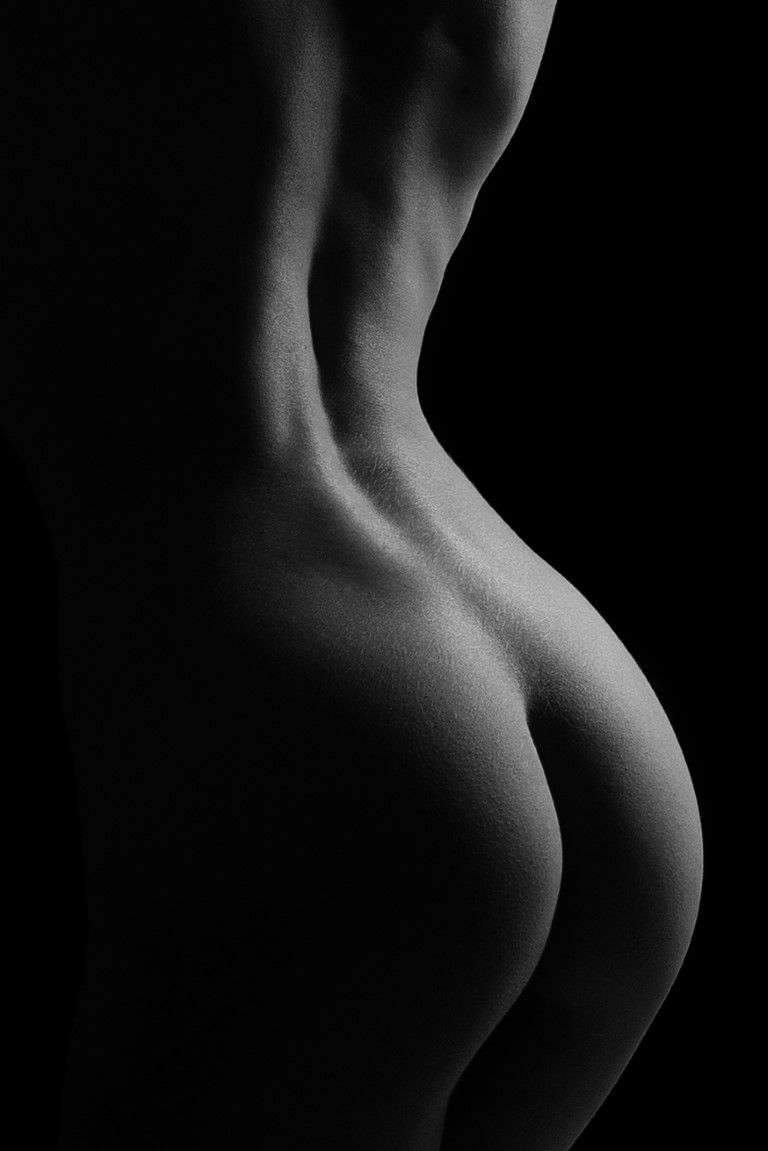 Black and white fine art nude photography highlighting the curves of a womans back and waist.