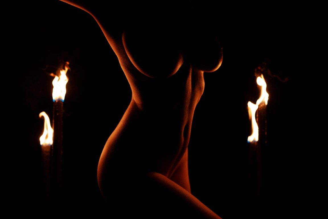 Silhouette du torse d'une femme nue entourée de quatre flammes ardentes sur fond sombre à Gavray.