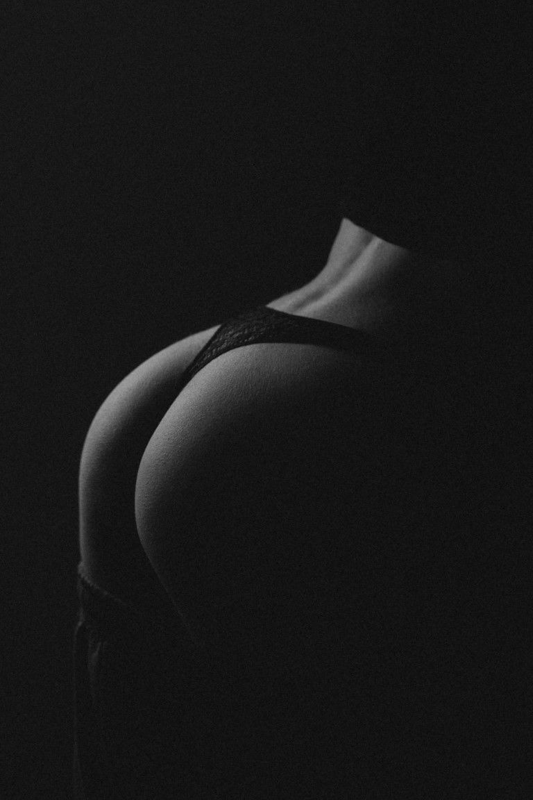 Photographie artistique discrète en noir et blanc des courbes d'une femme portant de la lingerie en dentelle noire.