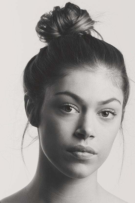 Portrait minimaliste en noir et blanc, en gros plan, d'une jeune femme aux cheveux relevés en chignon.