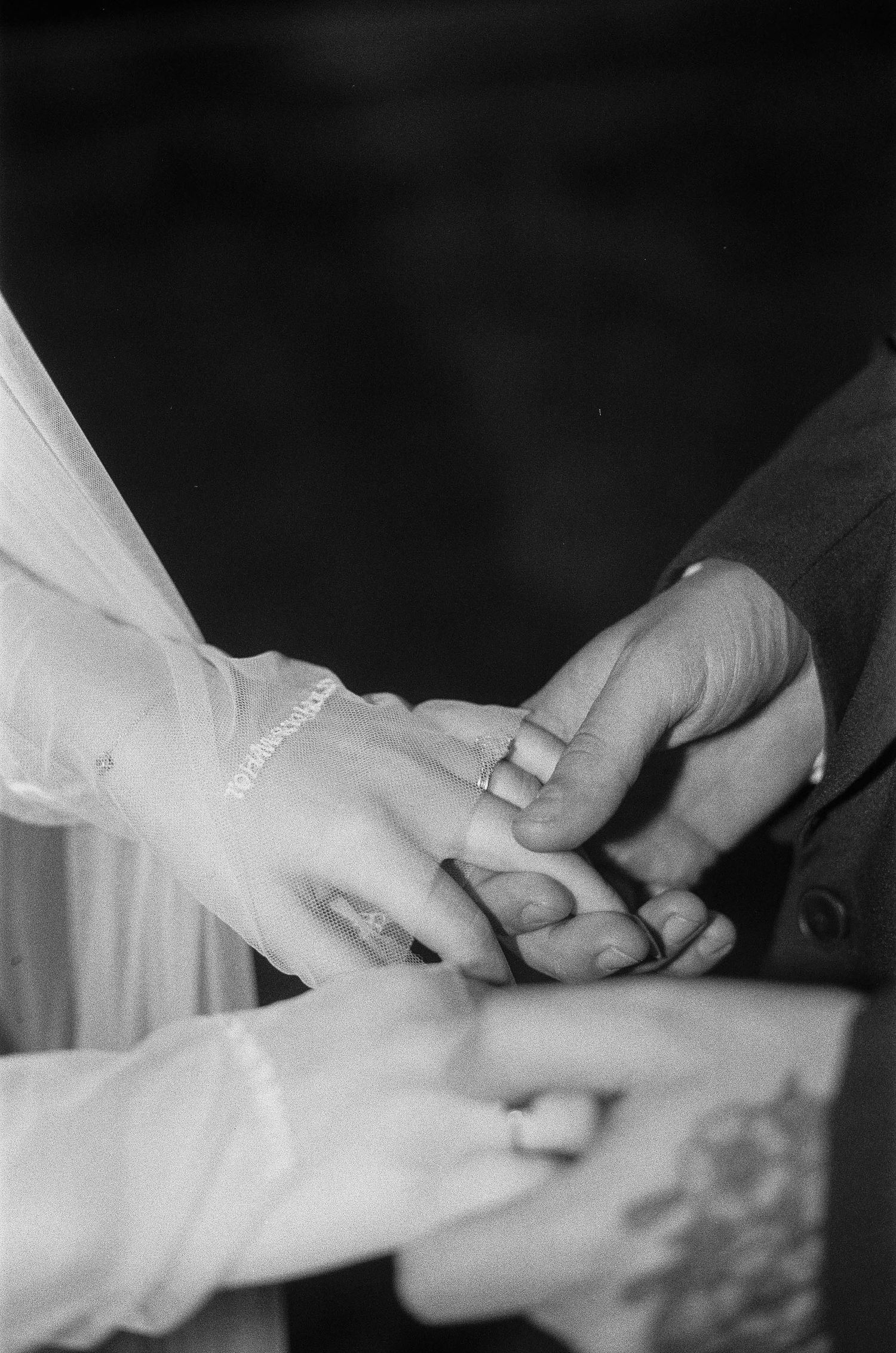 Black and white photo of a bride and groom exchanging wedding rings during a marriage ceremony.