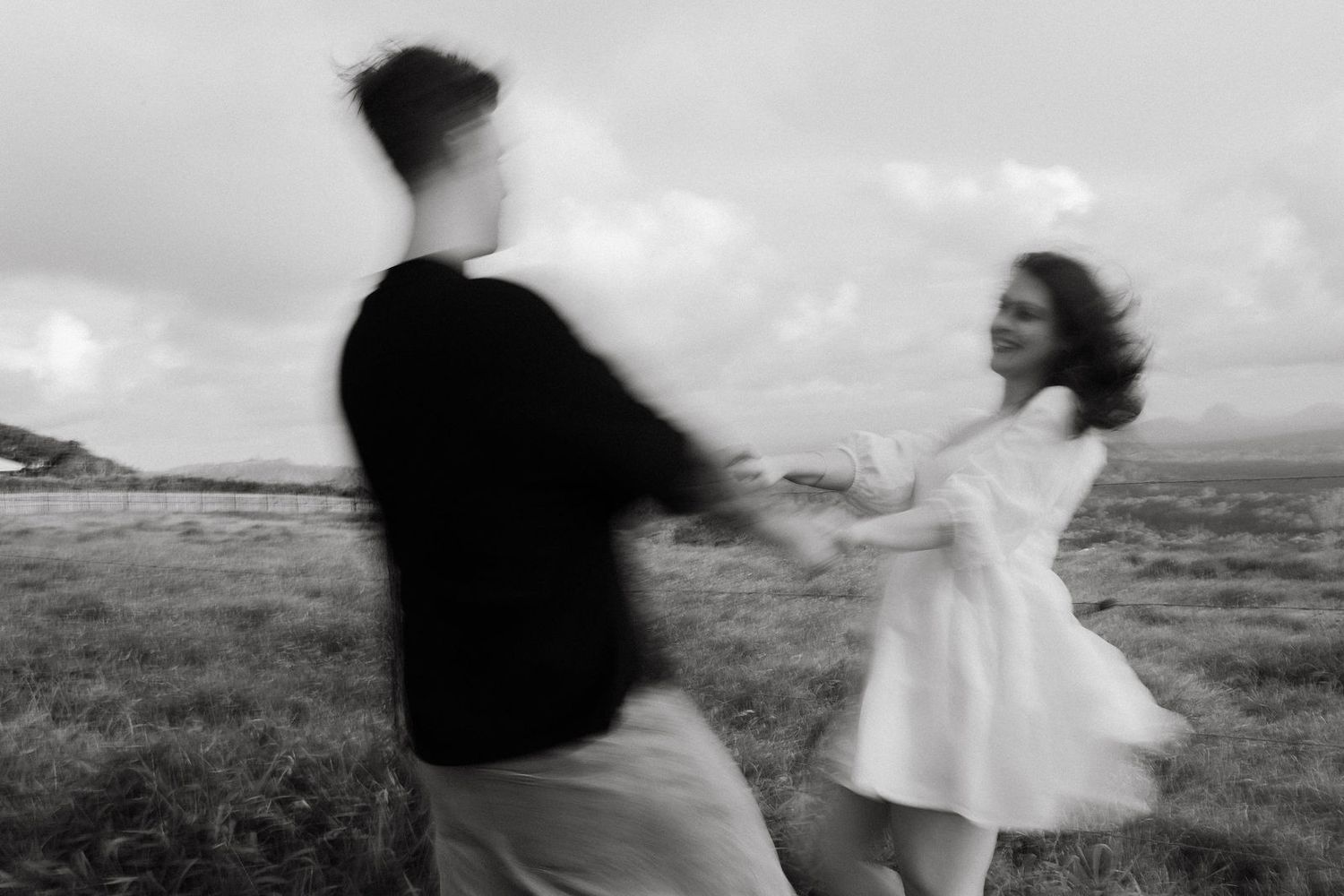 Black and white motion blur photo of a couple dancing and spinning together in an open field.