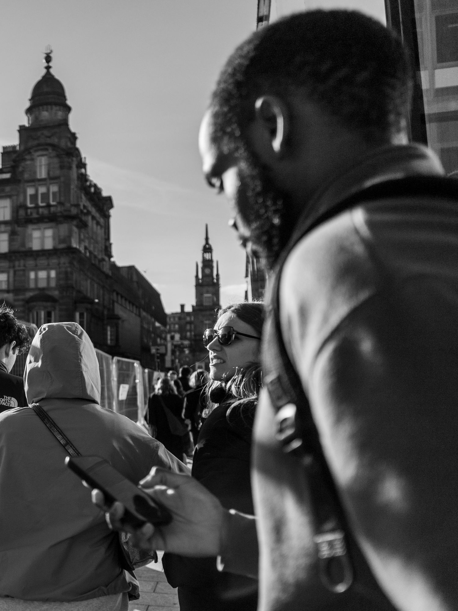 Street photo from glasgow featuring a woman looking towards the sun wearing sun glasses