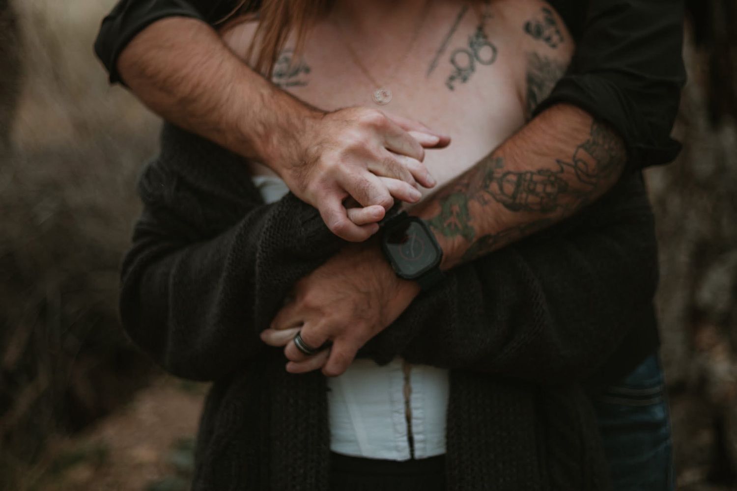 Artistic detail shot of tattooed arms and casual clothing in natural light.