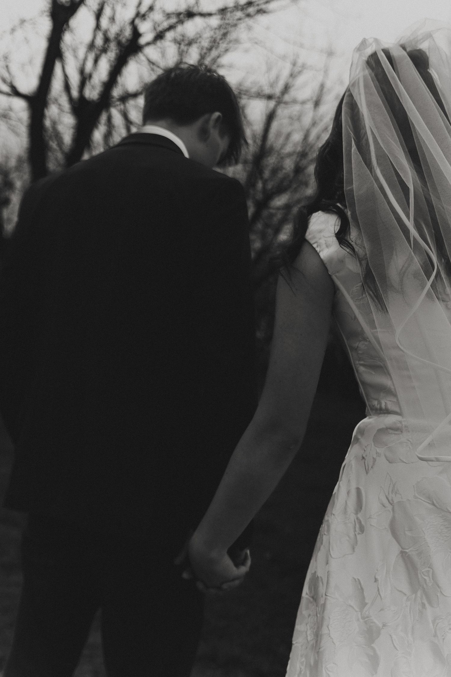 Black and white wedding photography capturing elegant silhouettes of a bride's dress and groom's suit.