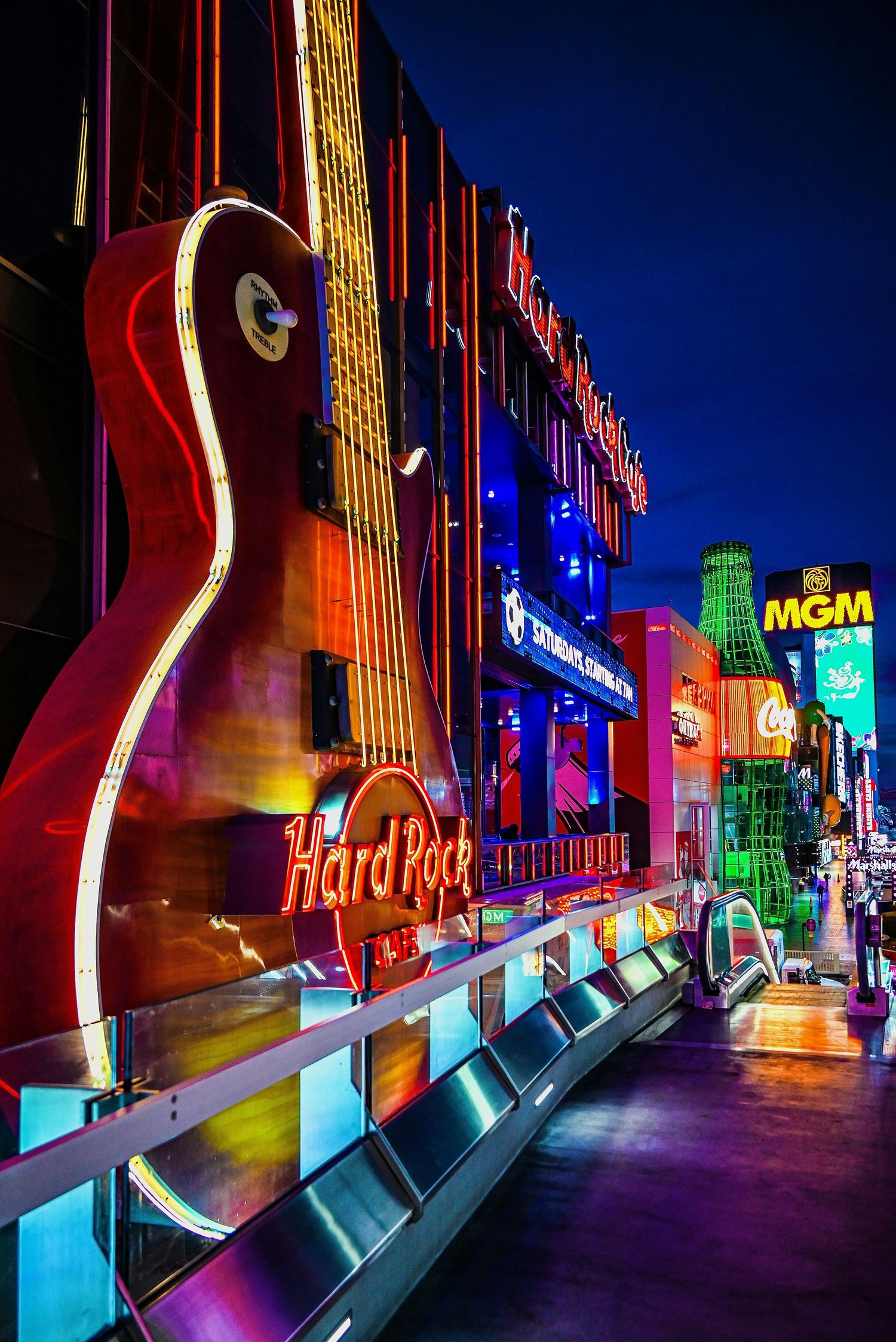 Neon-lit Hard Rock Cafe facade with giant guitar sign on the Las Vegas Strip at night.