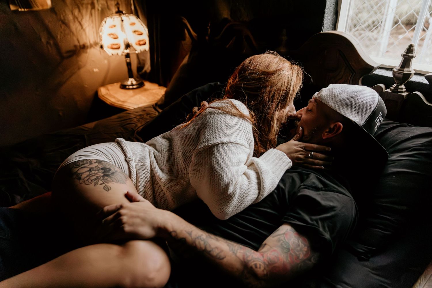 A couple embracing intimately in a cozy, dimly lit room.