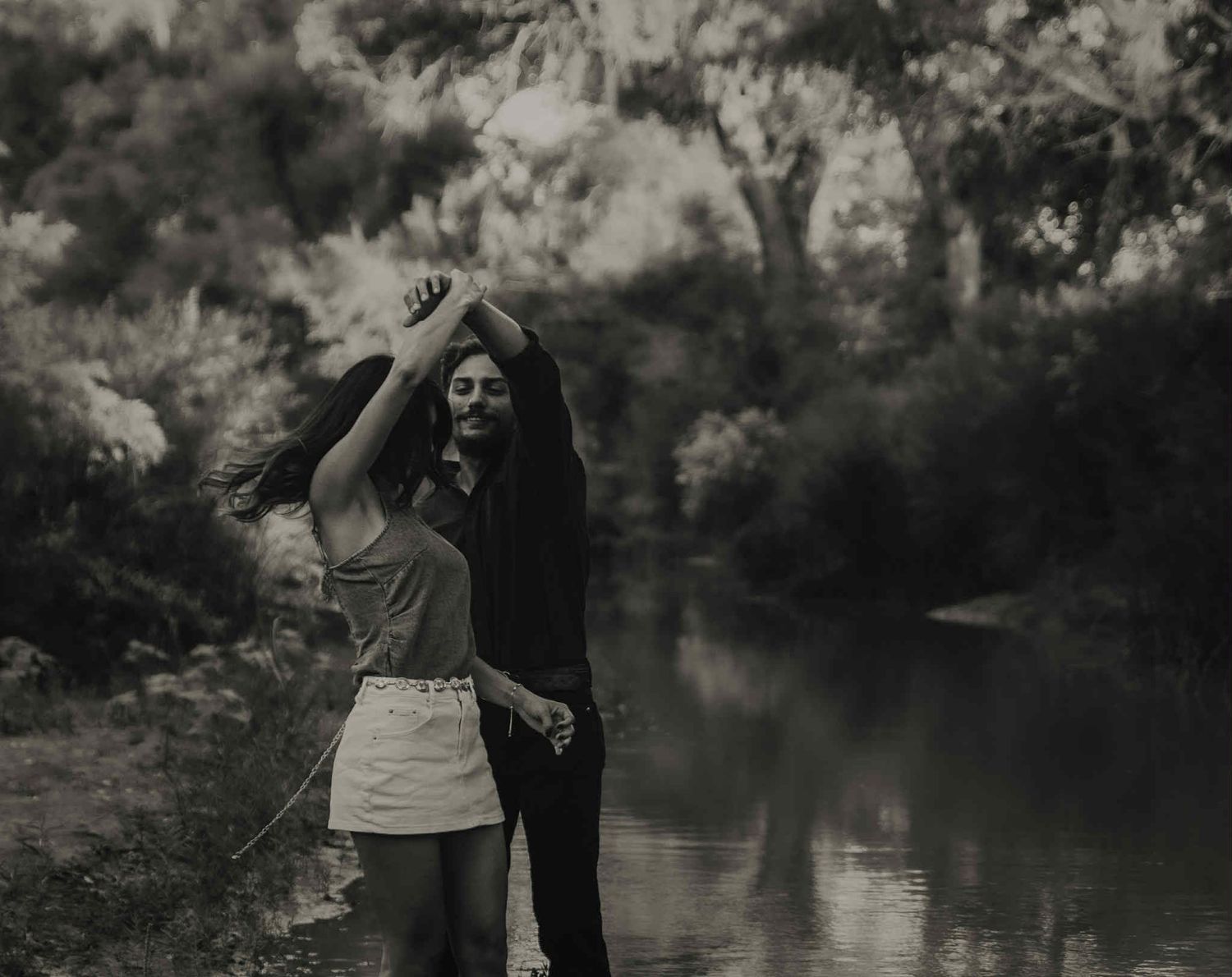 Atmospheric black and white photo of a couple by a serene waterside setting.