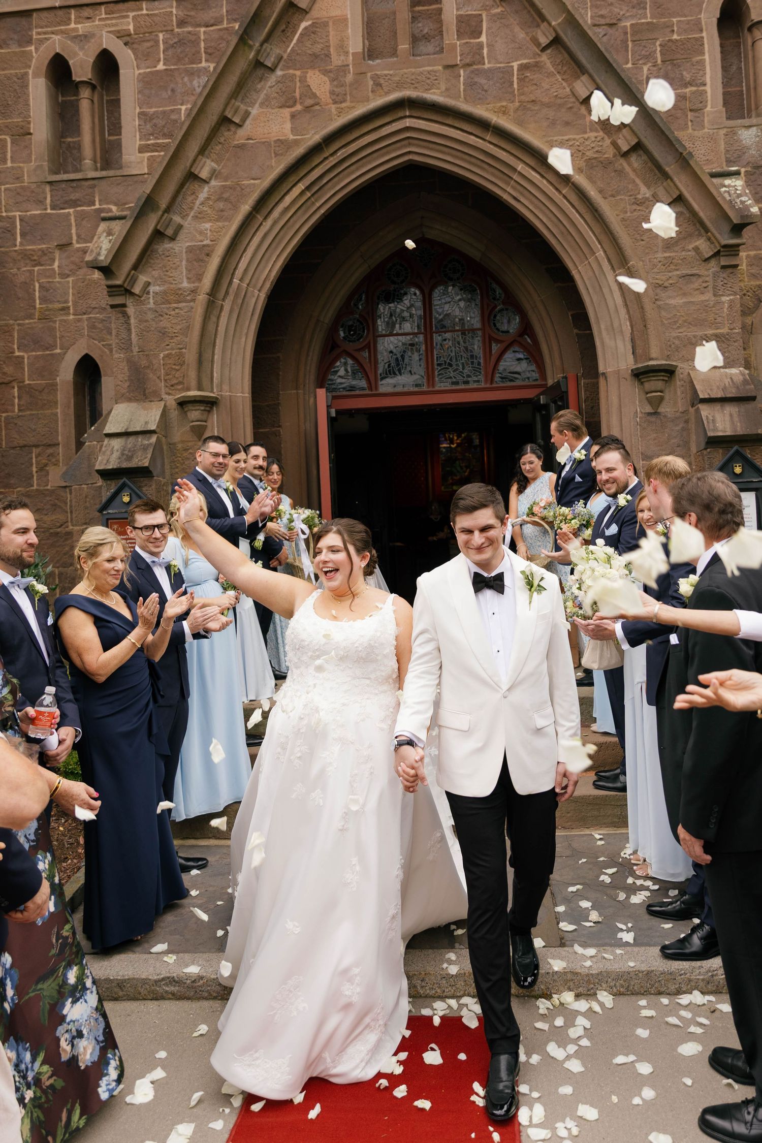 Bride and groom walking together our of a Catholic Church during their Rhode Island wedding.