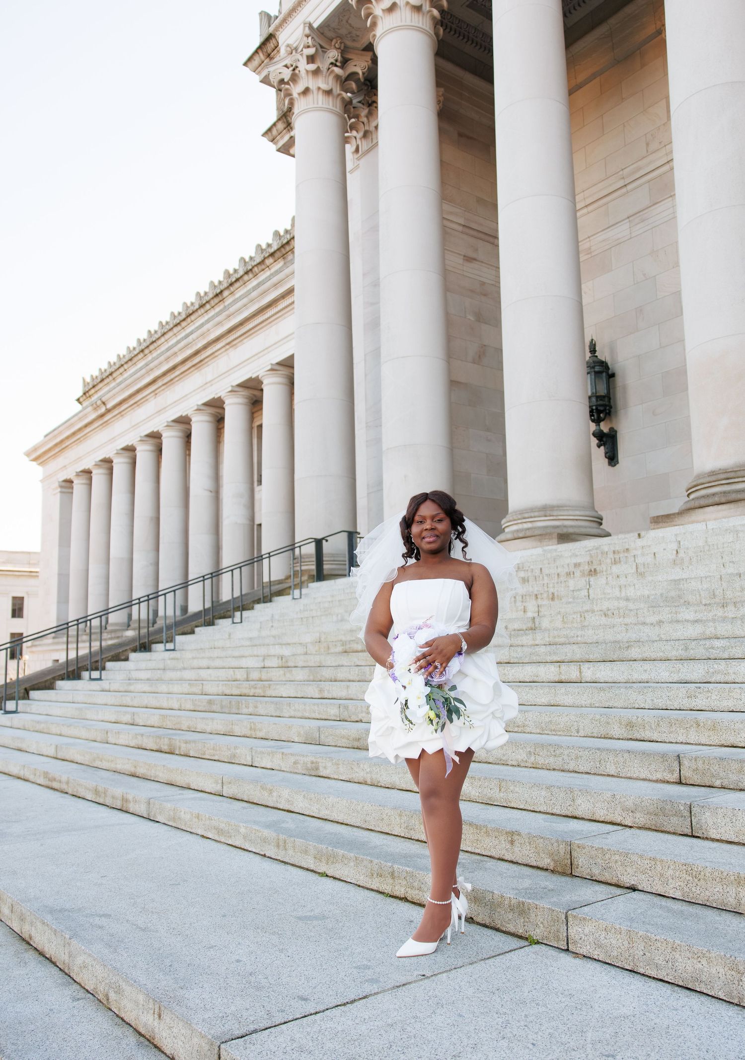 Bride posing with her bouquet beneath the columns of the Washington State Capitol in Olympia