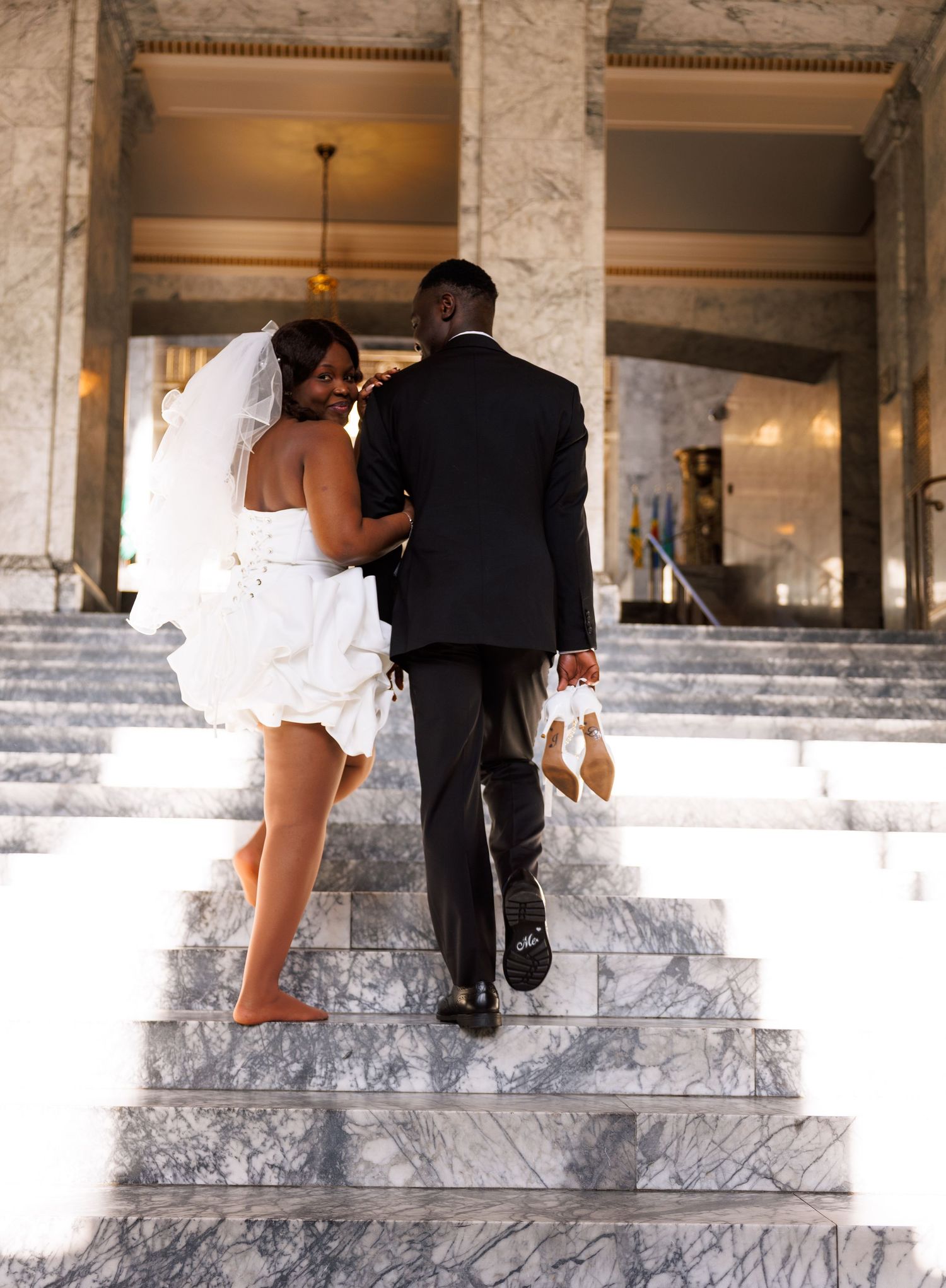 Newlyweds walking barefoot up the marble stairs inside the Washington State Capitol in Olympia