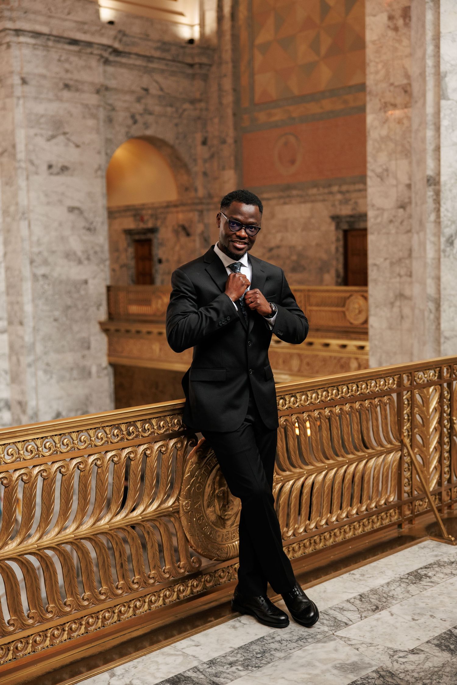 Groom adjusting his tie during a wedding portrait inside the Washington State Capitol