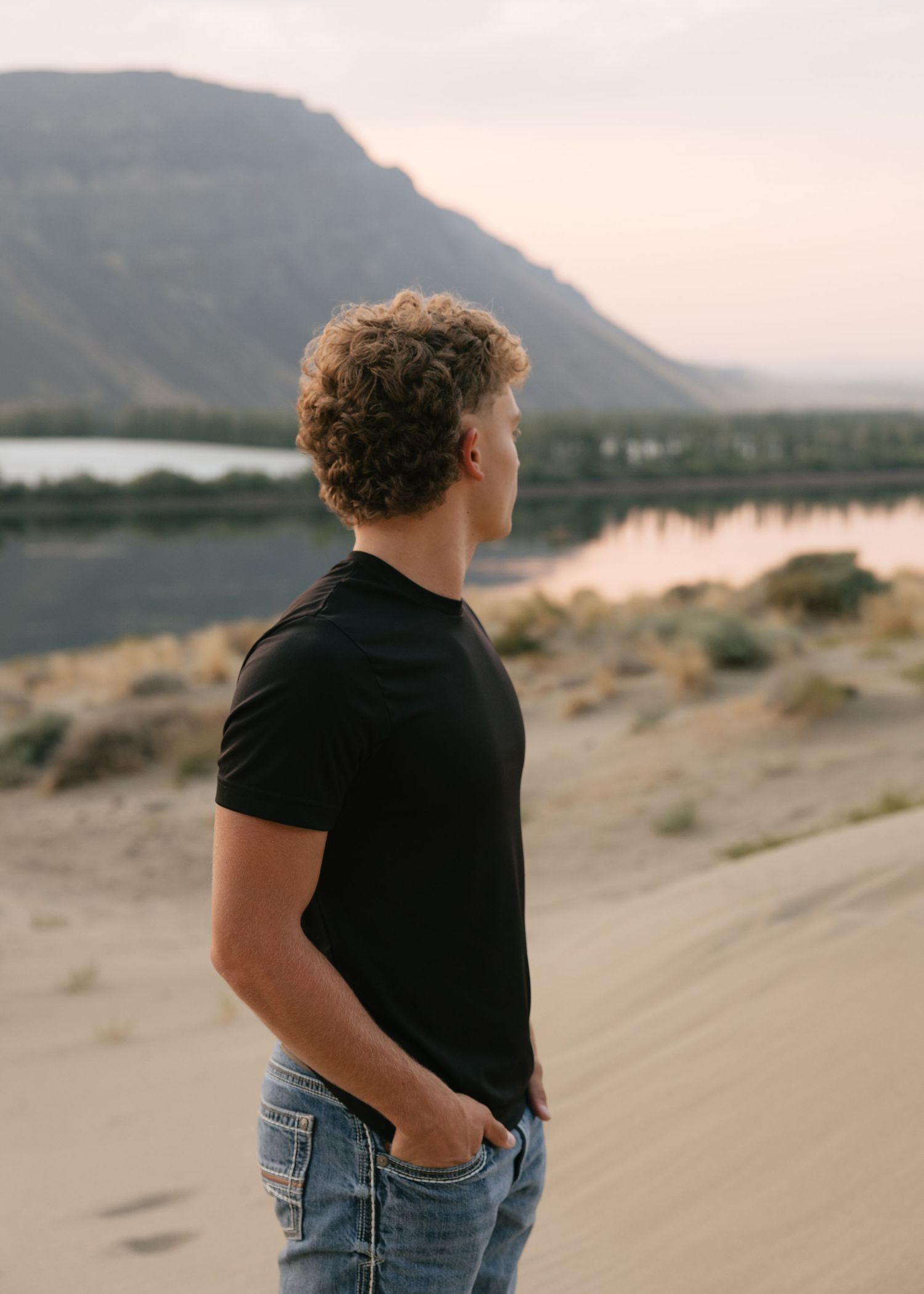 High school senior overlooking the river and mountains during a scenic outdoor senior photography session.