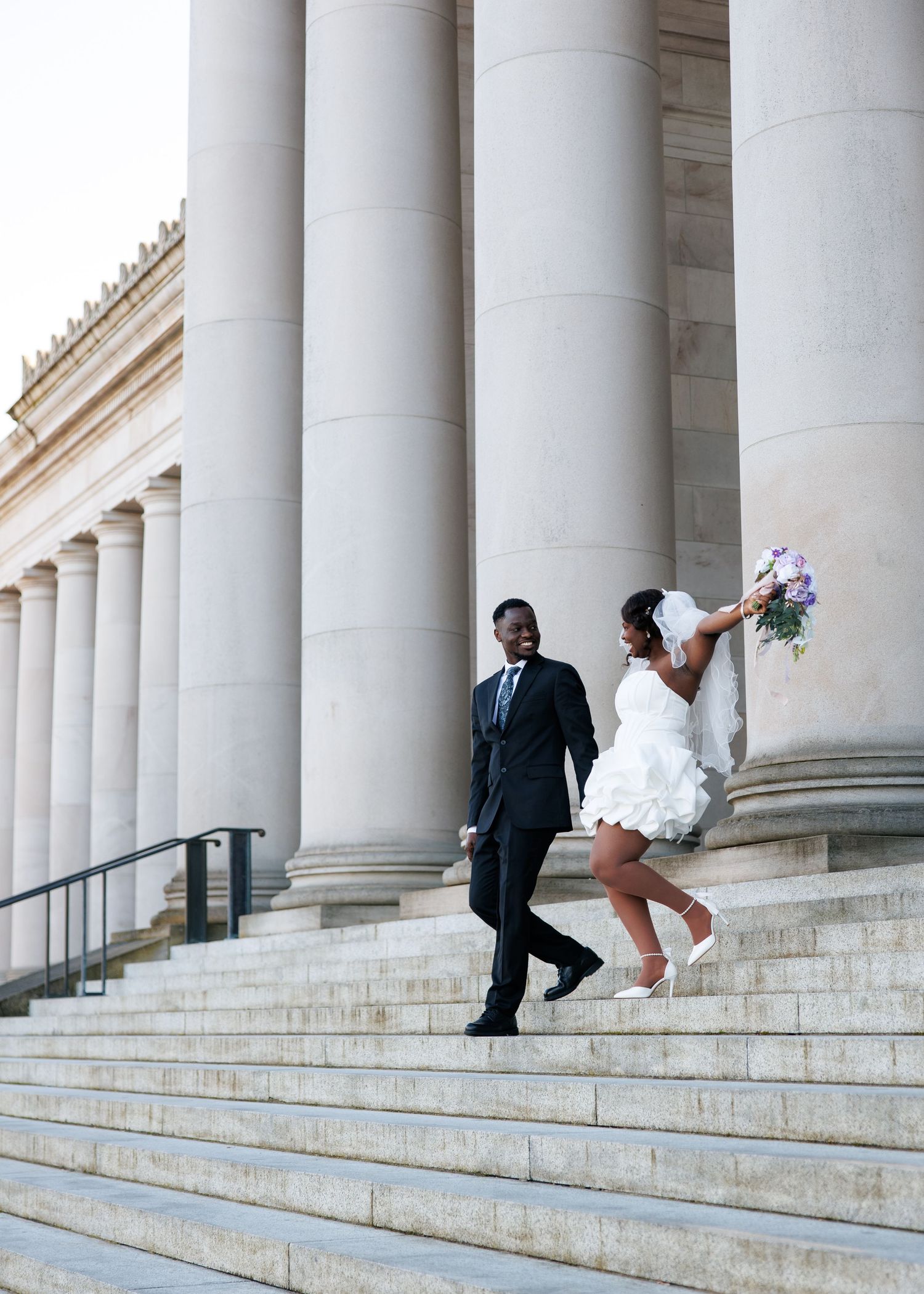 Joyful bride and groom walking beneath the columns of the Washington State Capitol in Olympia