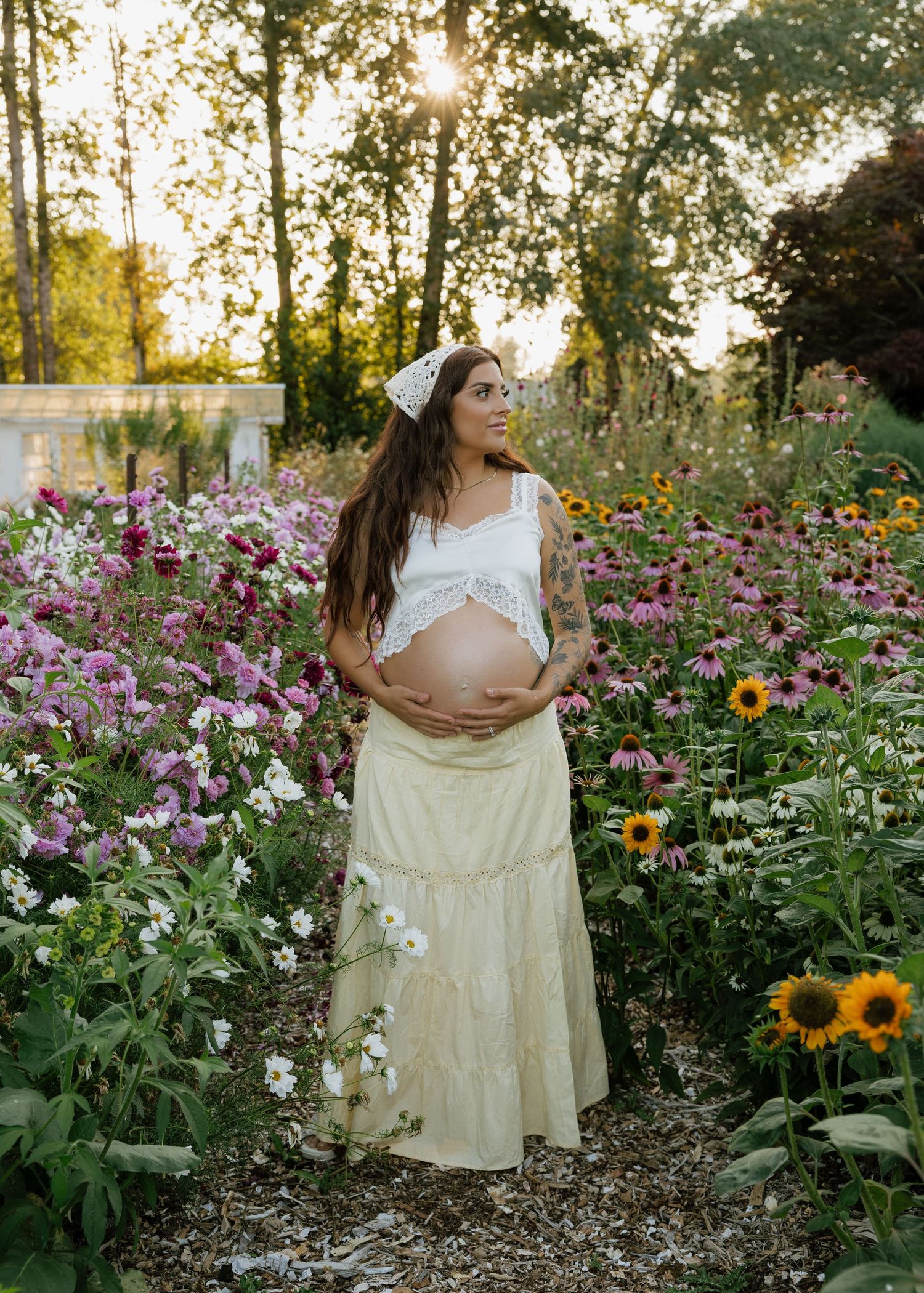 Expecting mother surrounded by colorful flowers during a dreamy outdoor maternity photography session in Washington.