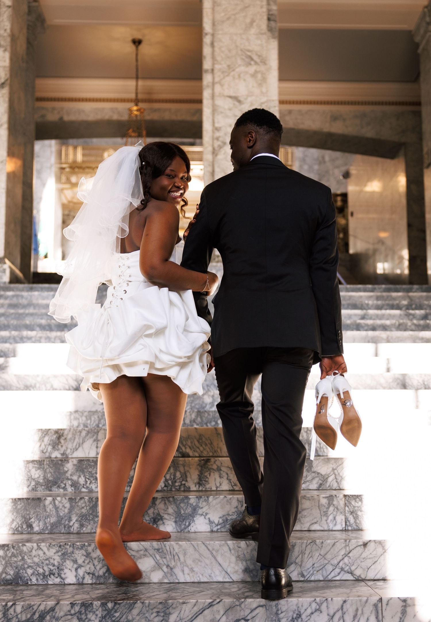 Candid bride and groom walking up the Washington State Capitol stairs after their wedding